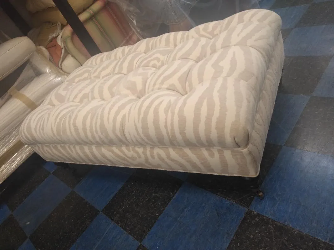 Beige patterned loveseat on a blue and black checkered carpet in a room