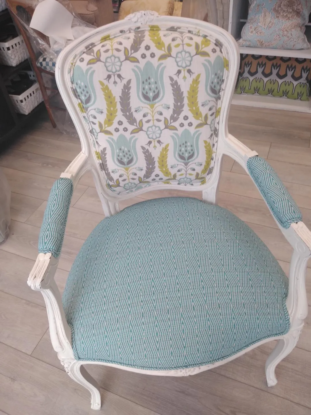 White vintage chair with patterned floral back and light blue cushion and armrests indoors