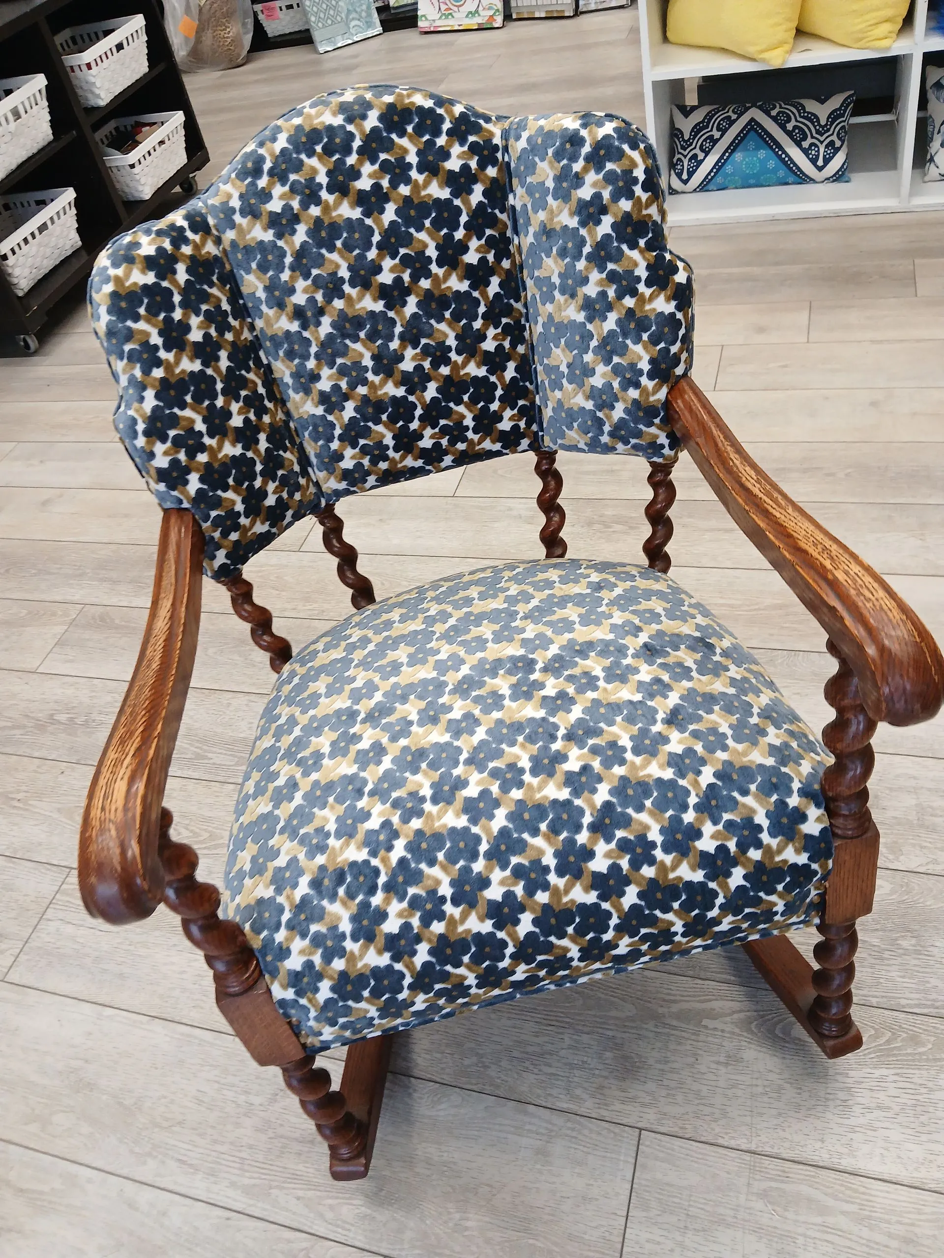 Blue floral upholstered wooden armchair with carved arms in a store showroom