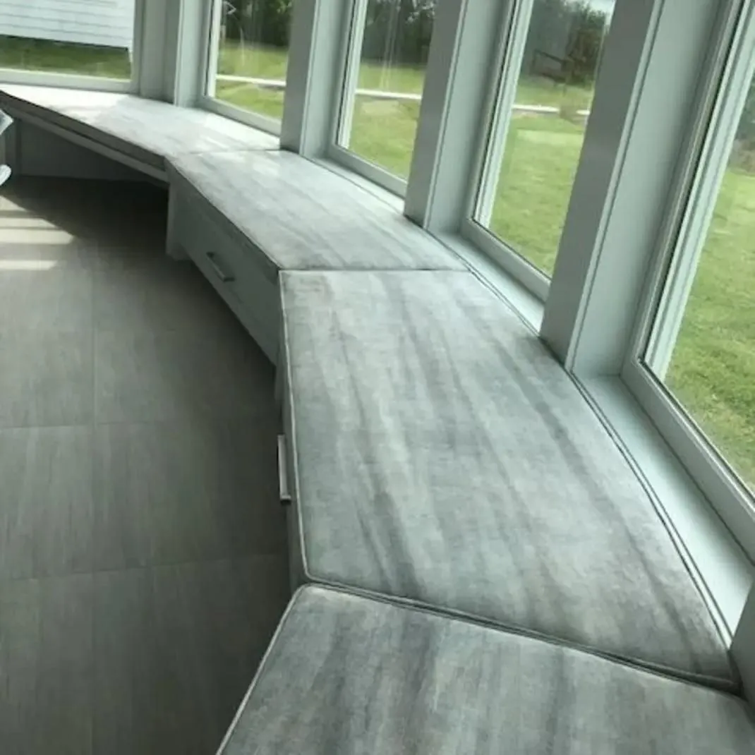 Curved built-in bench seating by large windows in a bright room