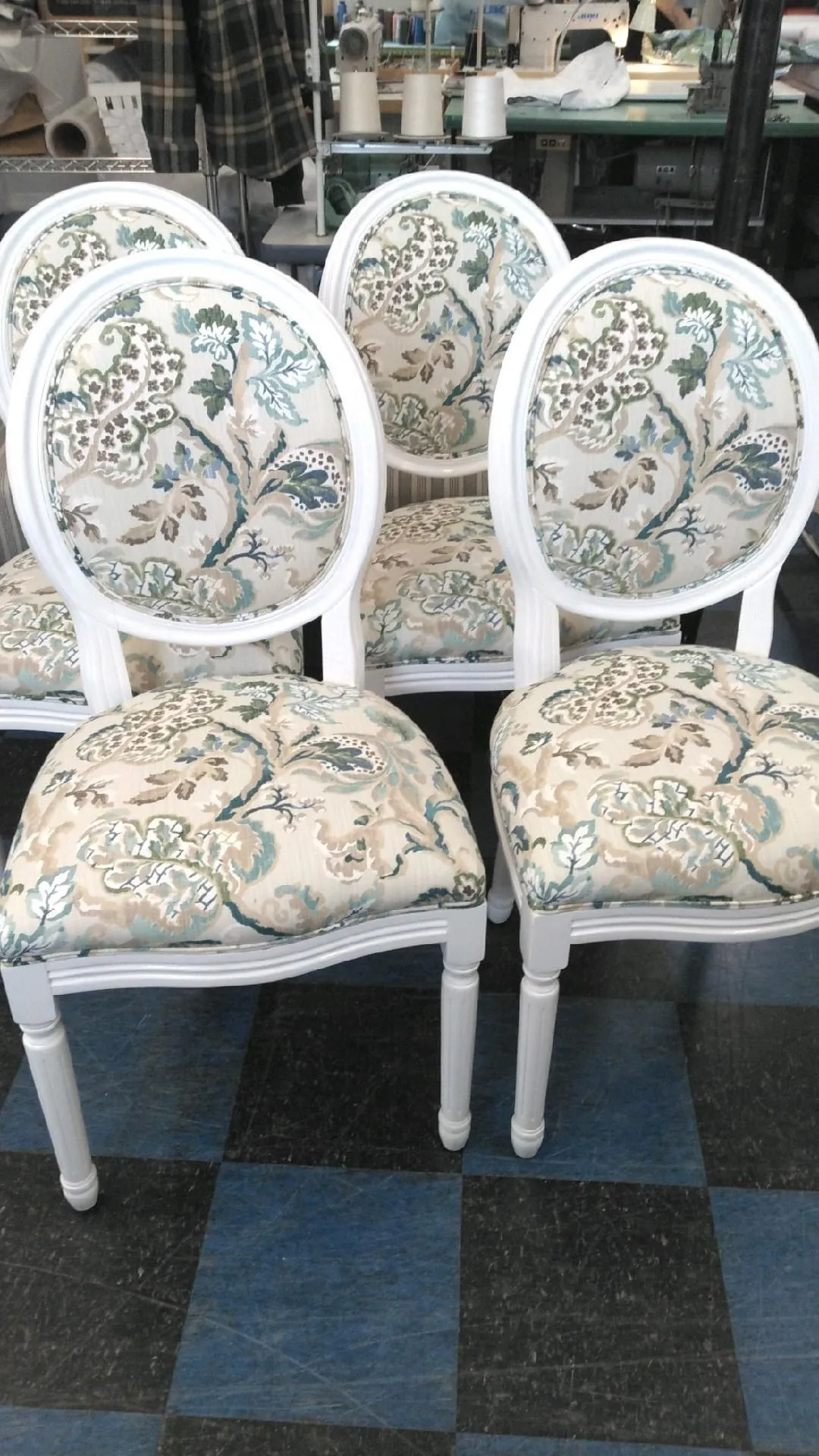 Two ornate white-upholstered chairs with floral patterns in a shop display
