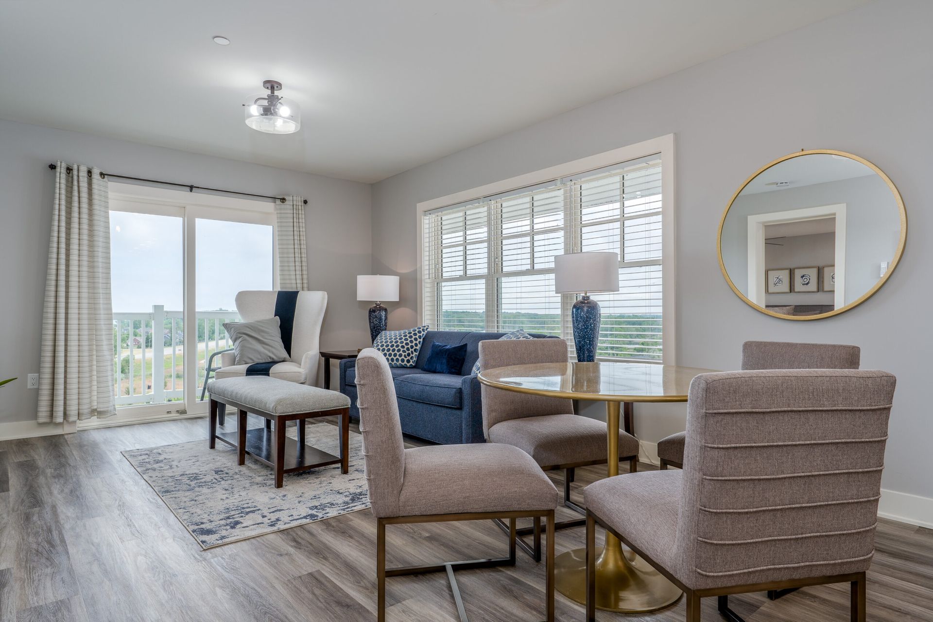 A living room with a couch , chairs , a table and a mirror.