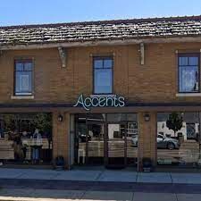 The front of a brick building with a sign that says accents on it.