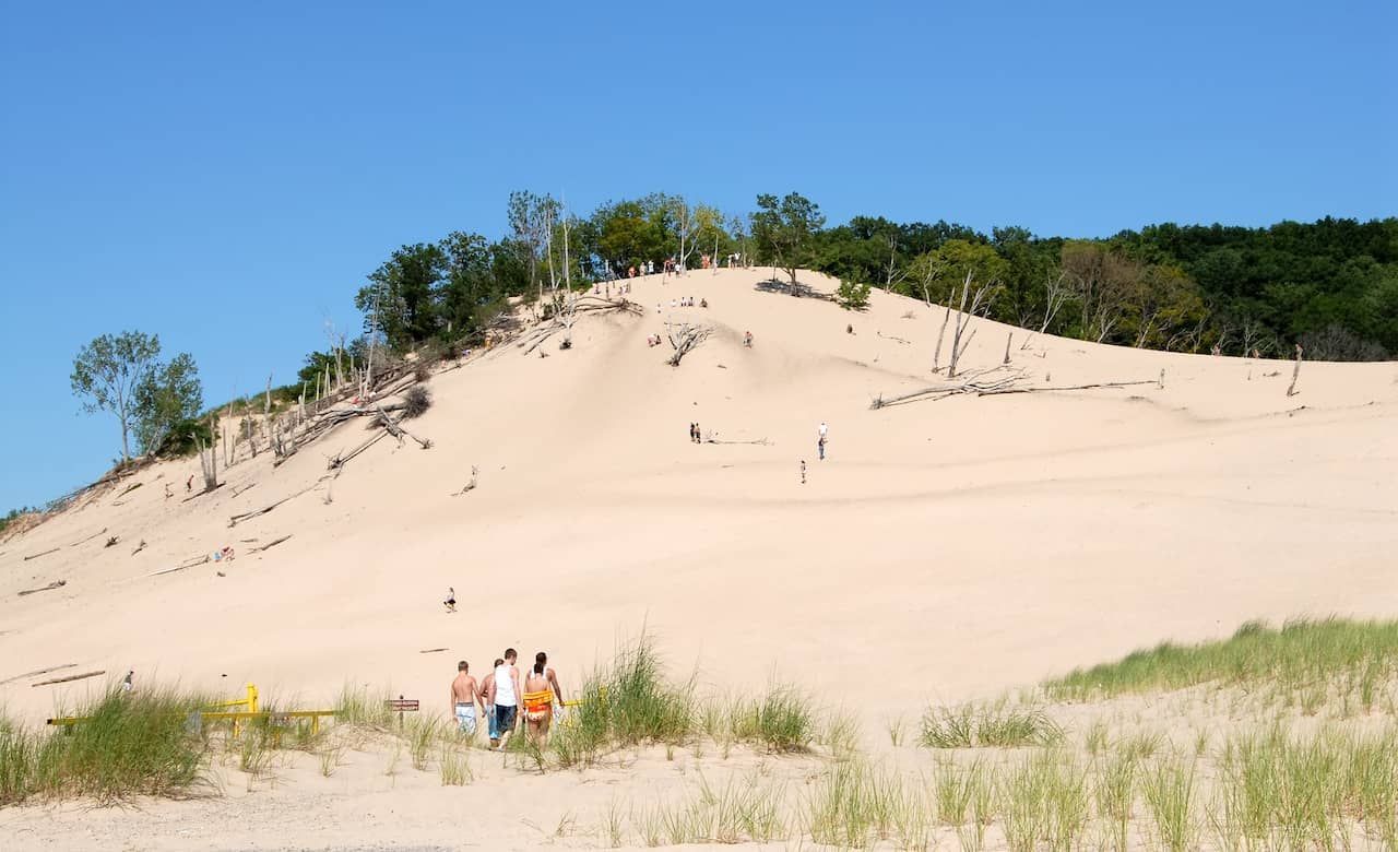 A group of people standing on top of a sand dune.