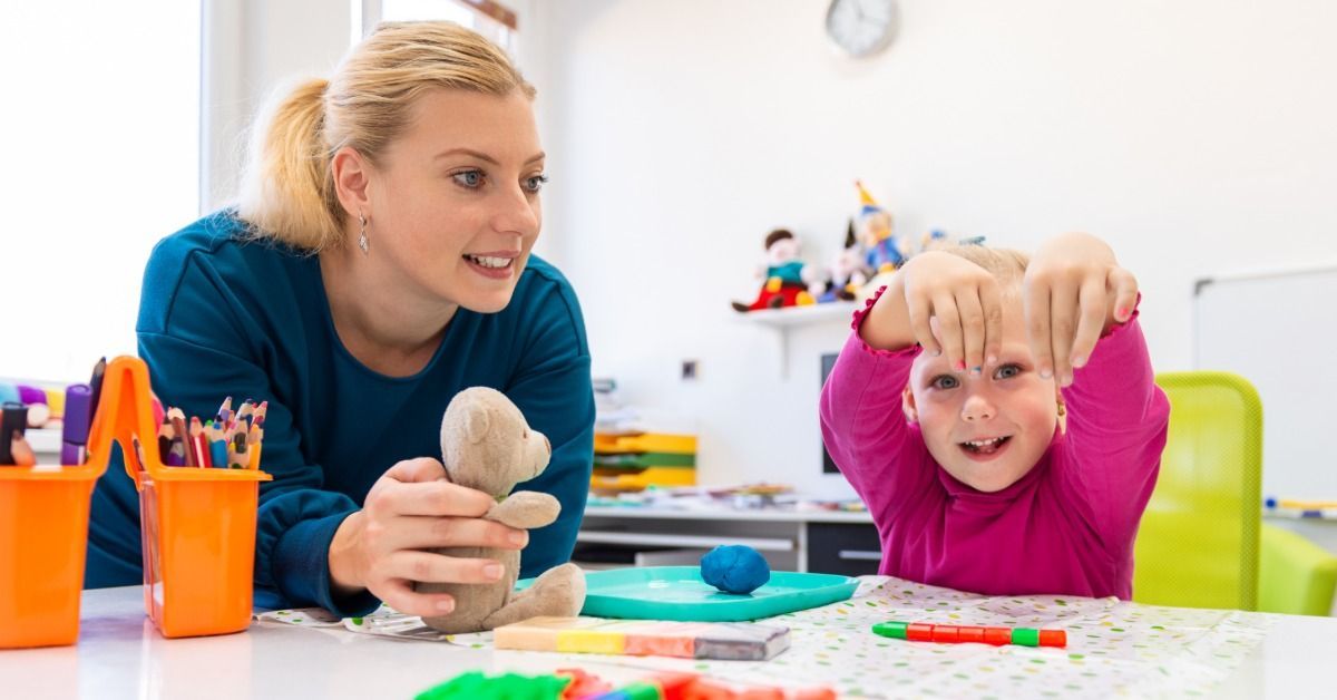 A therapist guides a girl through a colorful sensory activity with clay, toys, and art supplies at a