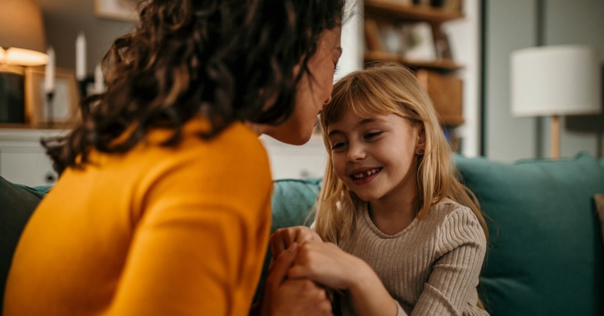 A girl sits between a parent and a teacher as they review the girl's IEP together at a table in a classroom.