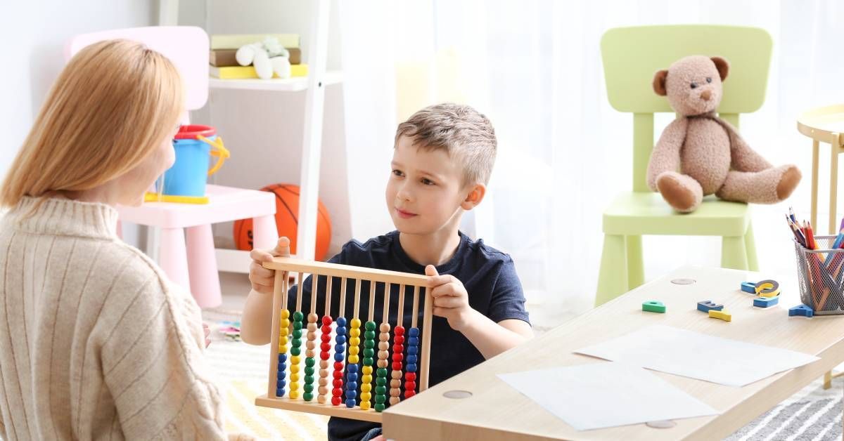 A child sitting at a table and showing his therapist the pattern he made using his developmental toy.