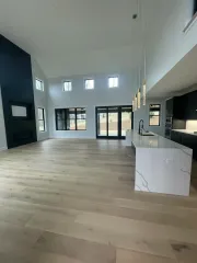 Spacious modern living room with high ceilings, light wood floors, and marble kitchen island
