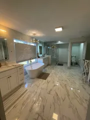 Luxurious marble bathroom with freestanding tub, double vanity, glass shower, and bright ceiling lights