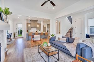 Bright open-plan living room with blue sofa, wood floors, and kitchen in the background