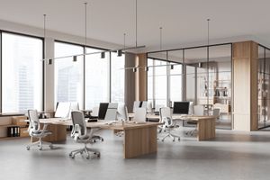Modern open-plan office with white desks, swivel chairs, and large windows overlooking a city.