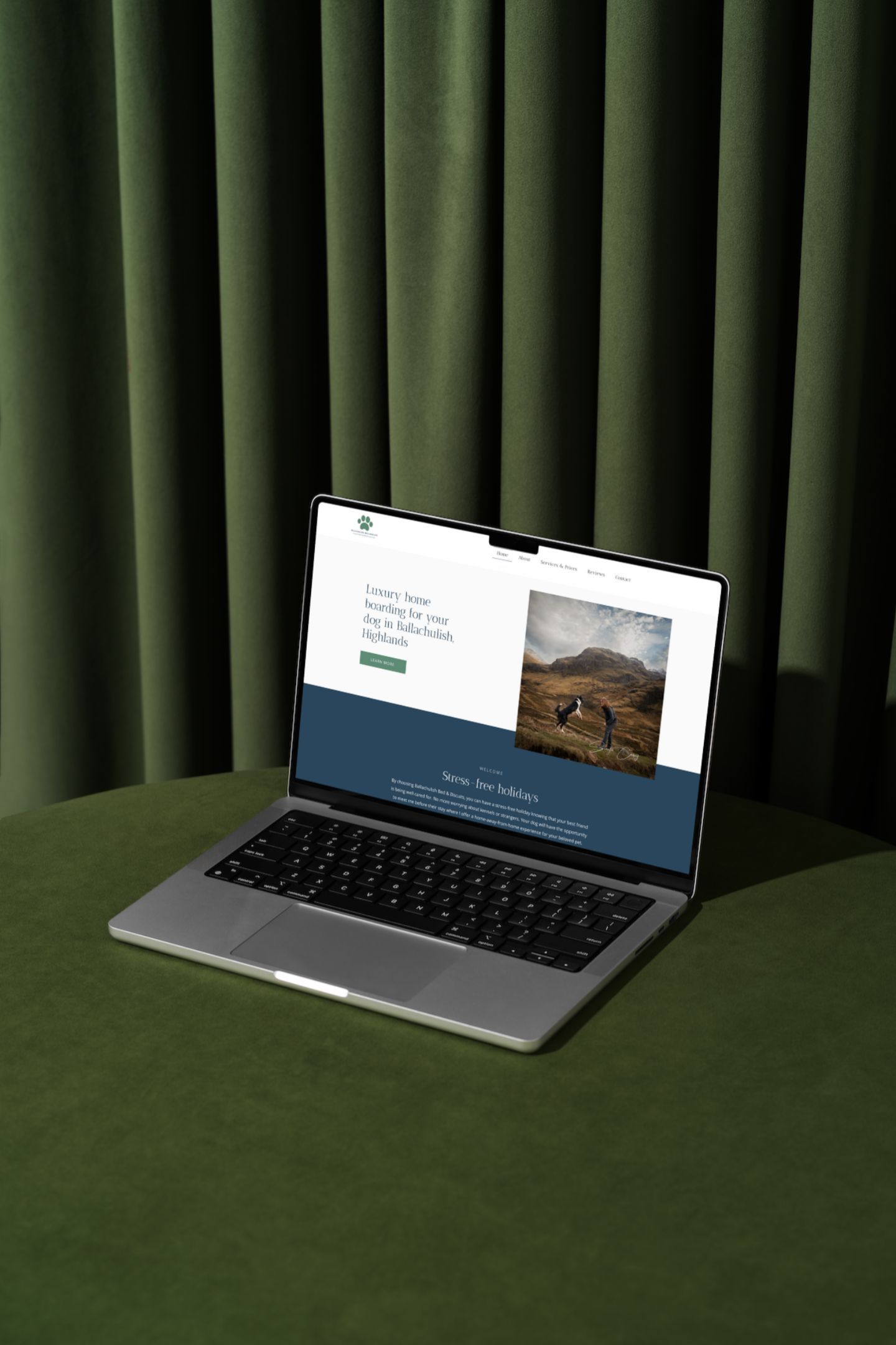 A laptop computer is sitting on a green table in front of a green curtain.
