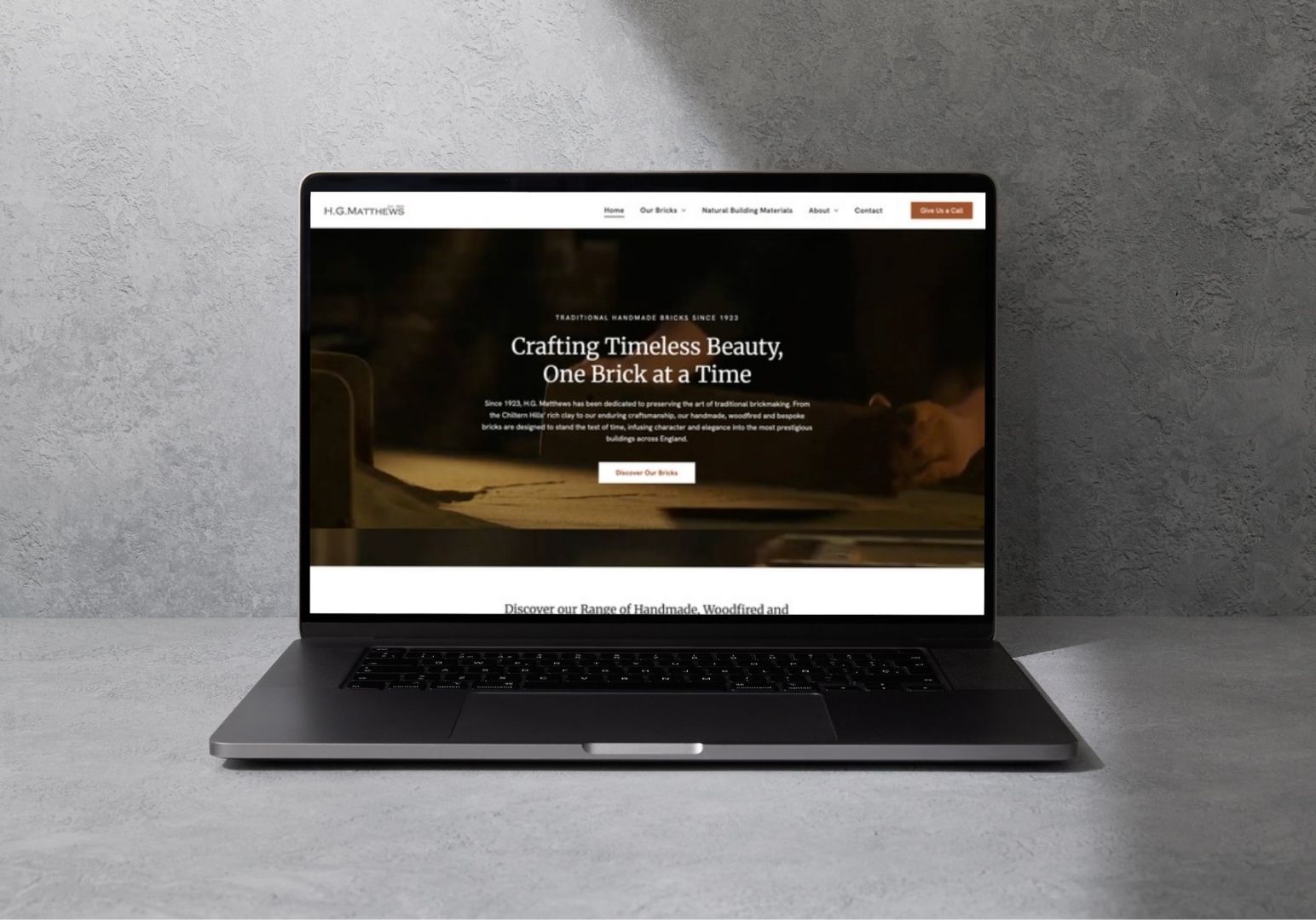 A laptop open on a textured gray surface displaying a website with a