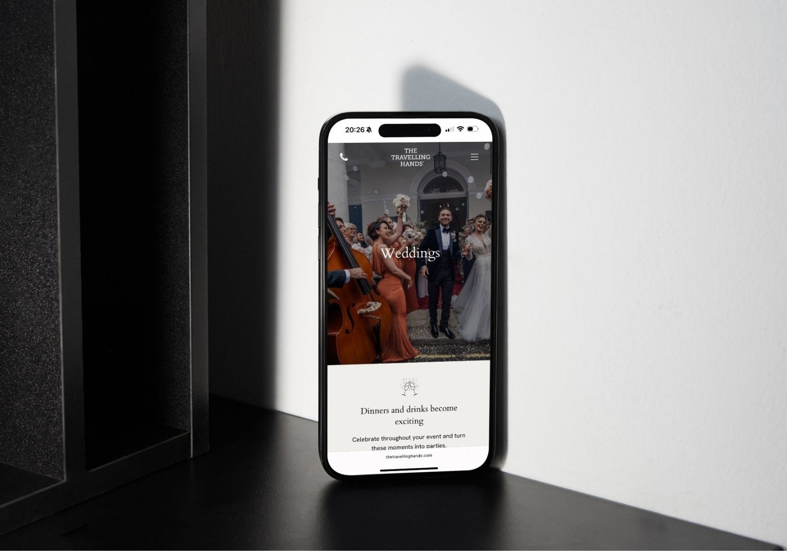 A smartphone displays a photo of a bride and groom walking down the aisle after a wedding ceremony, resting on a table.