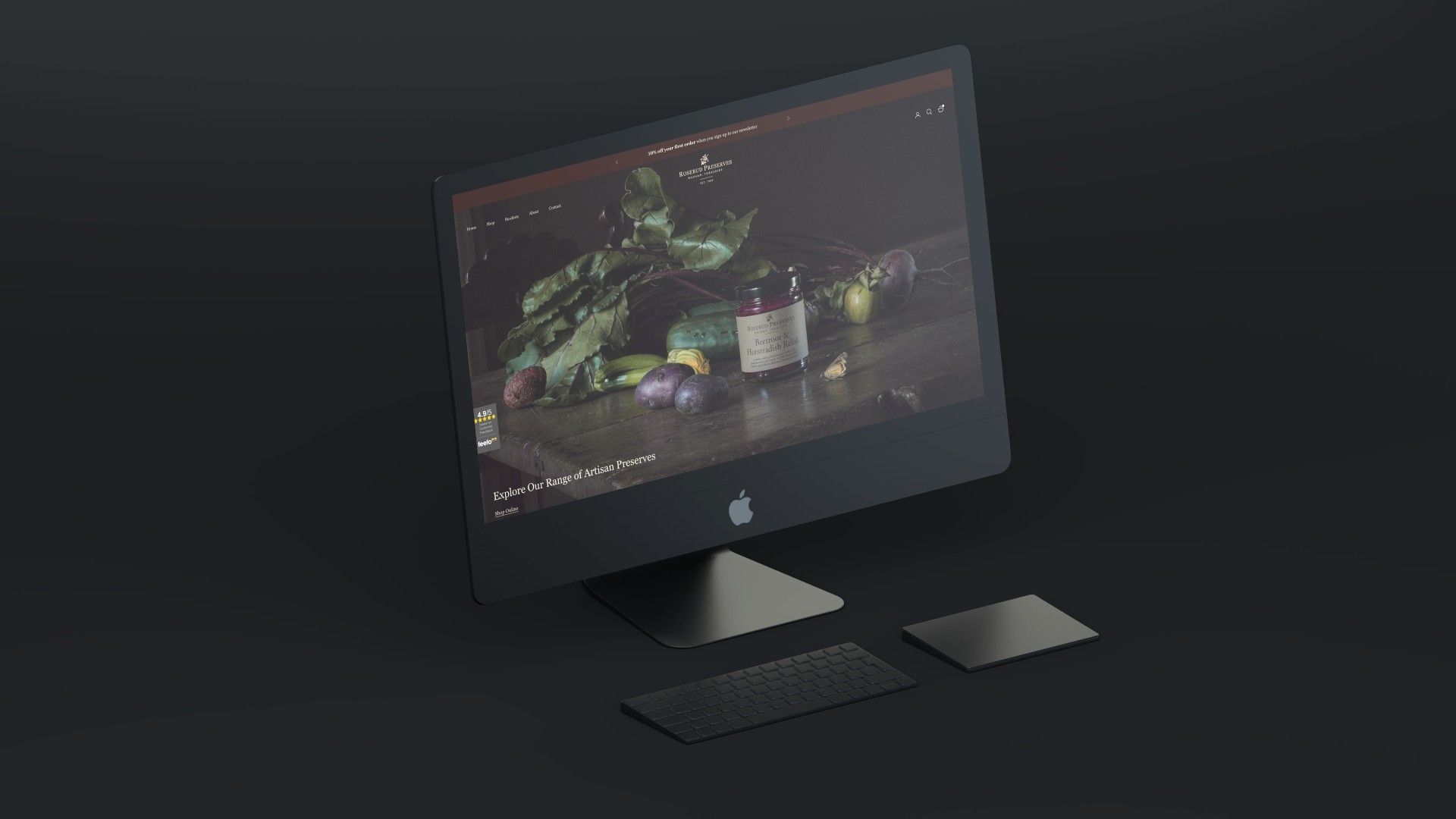 A sleek, dark-themed Apple desktop computer setup with a keyboard and trackpad against a matching minimalist background.