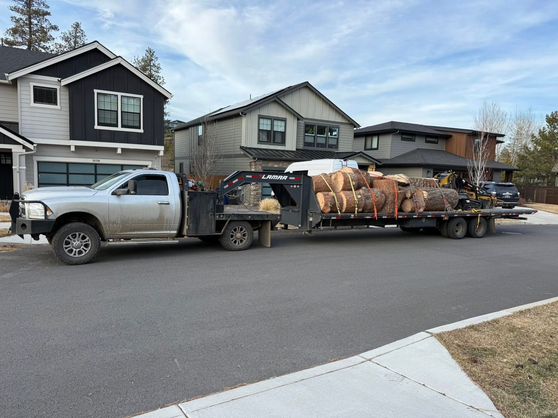 Pickup truck hauling a loaded trailer on a suburban street, with houses in the background.