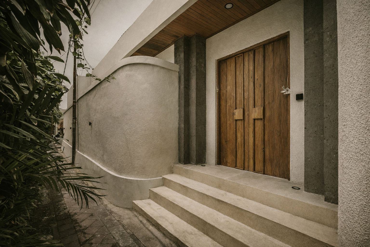 Wooden door with steps leading up to an entry. Exterior shot with greenery and stucco walls.