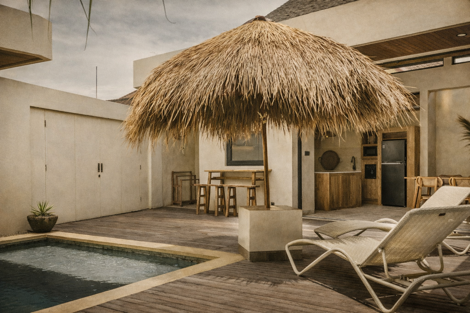 Poolside patio with thatched umbrella, lounge chairs, small bar, and a pool.