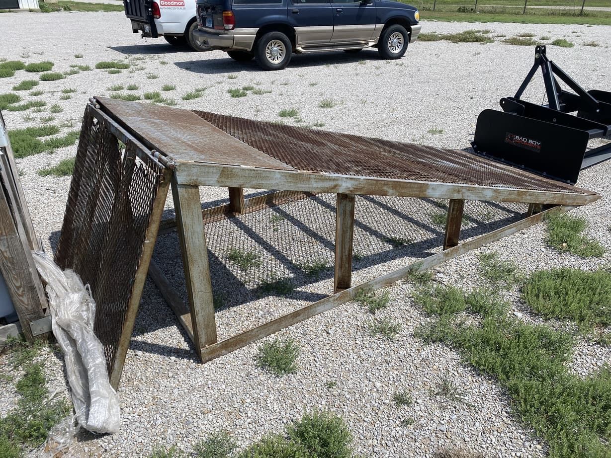 A truck is parked next to a ramp in a gravel lot.