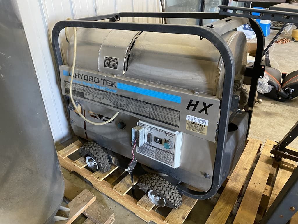 A stainless steel steam cleaner is sitting on top of a wooden pallet.