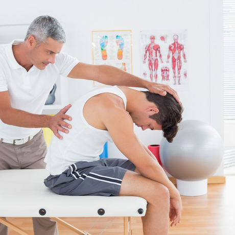 Physical therapist supporting a seated patient during a back assessment in a bright clinic