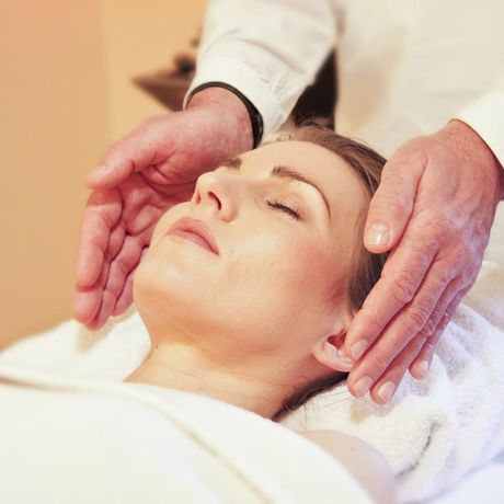 Spa therapist giving a relaxing facial massage to a client lying on a towel
