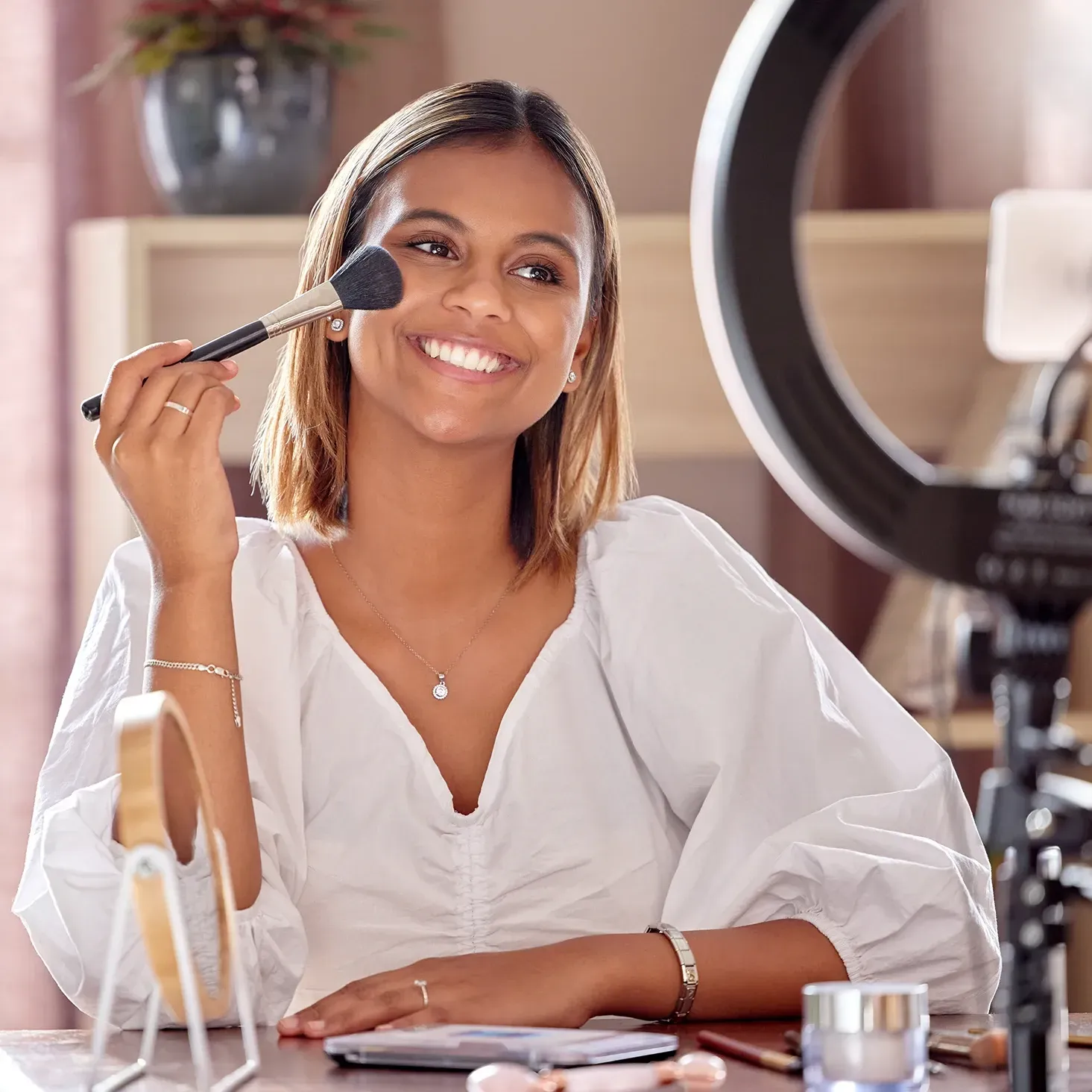 Young beauty influencer recording a make-up tutorial video inside her home