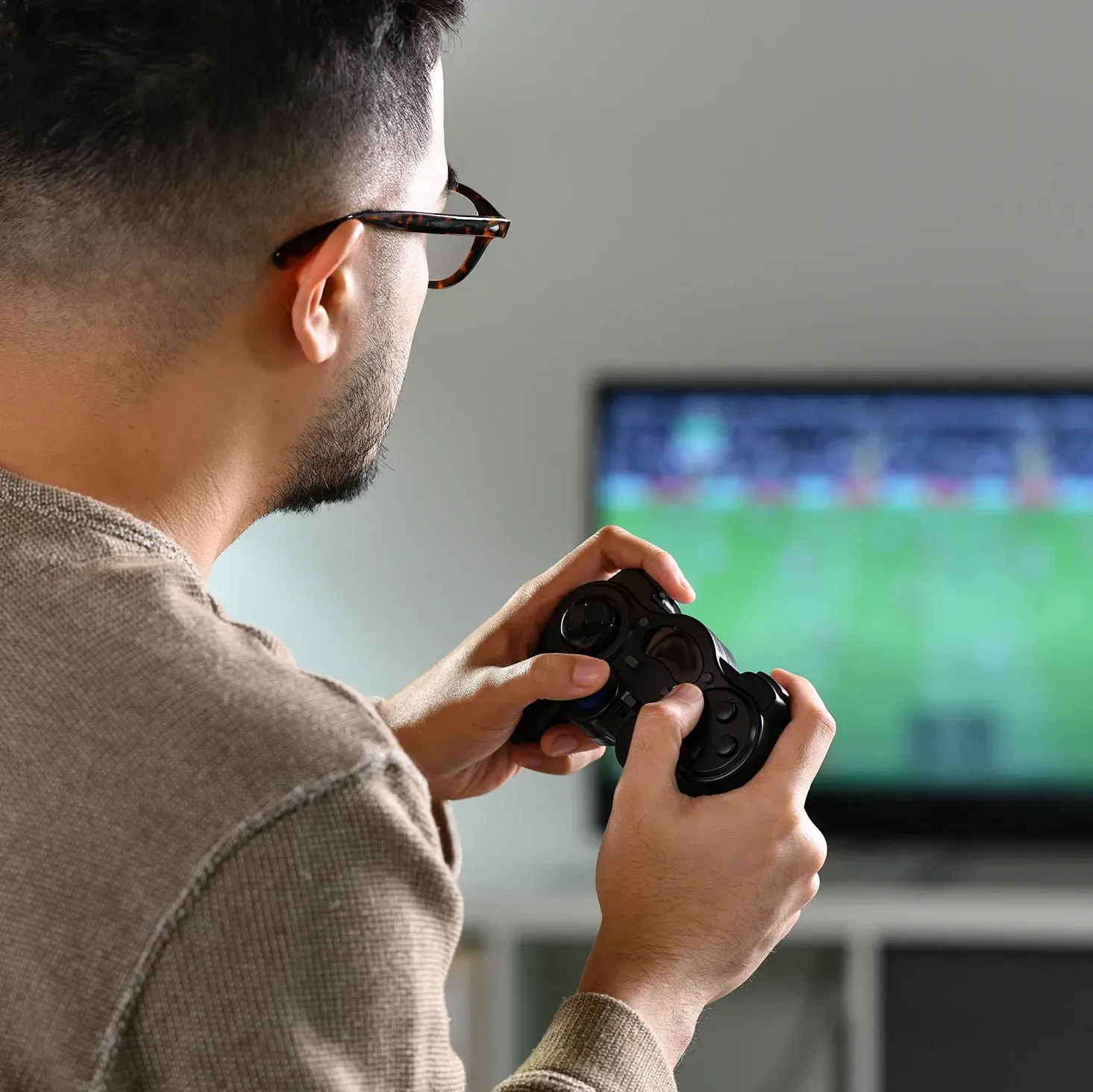 Male gamer playing a sports game on a large television