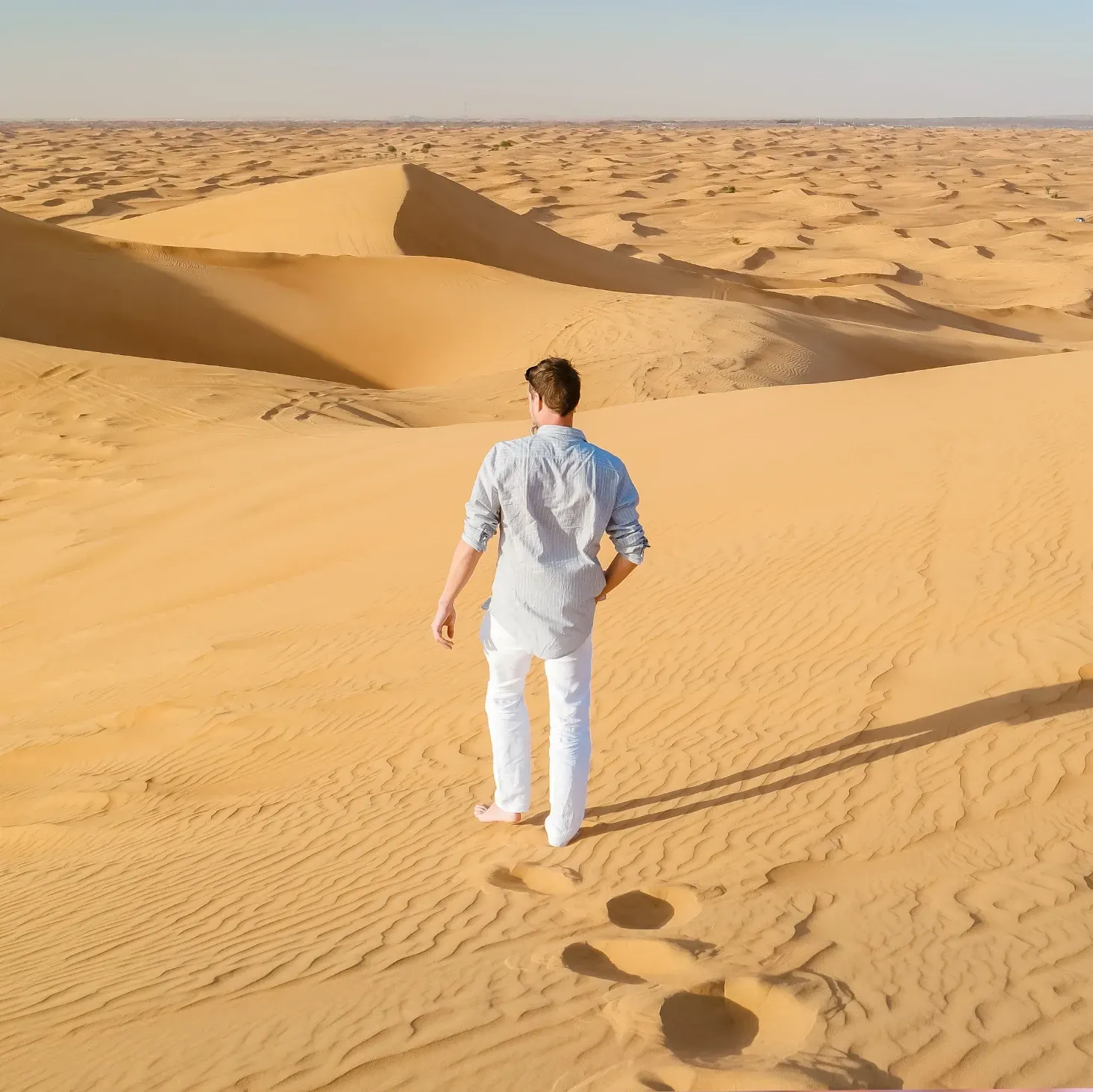 Male social media influencer walking on the sand dunes in Dubai