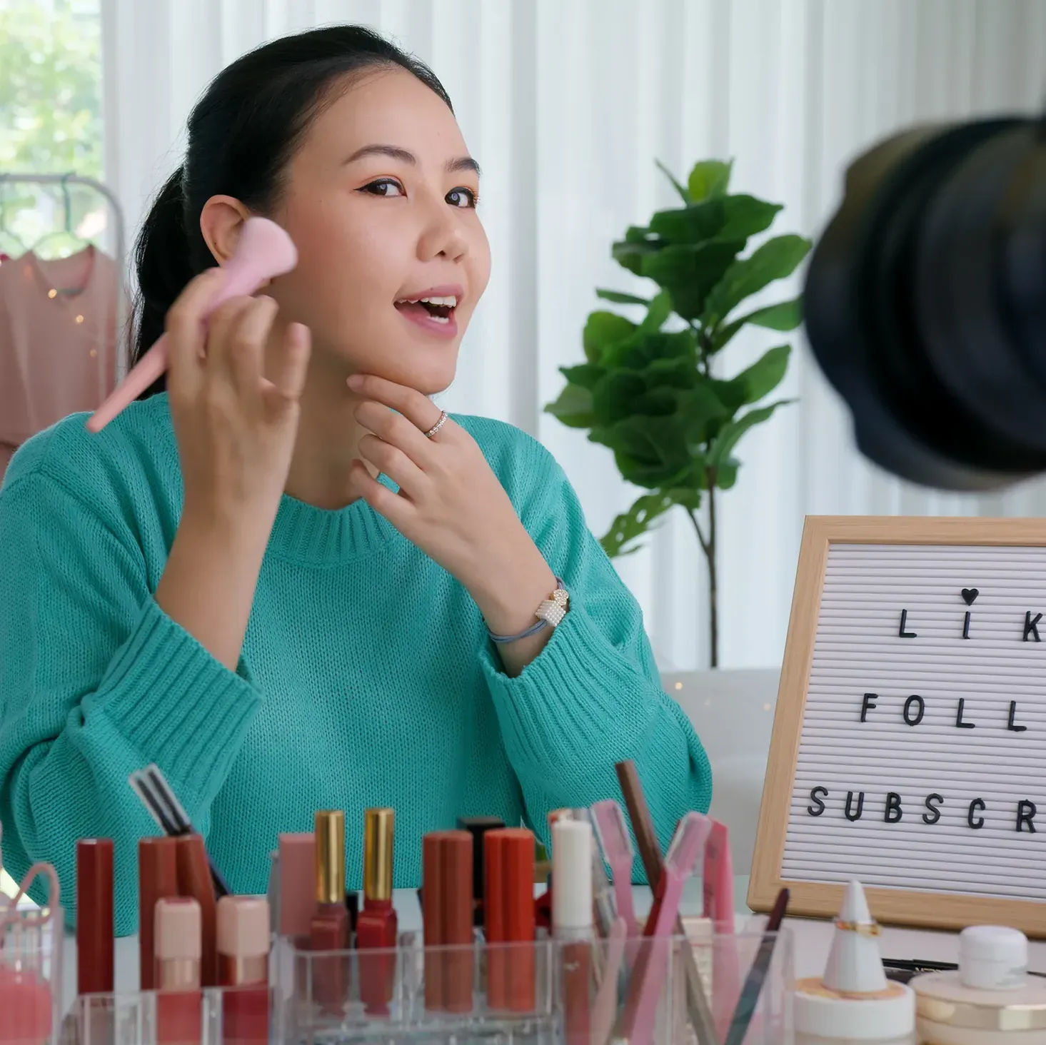 Young, beauty influencer recording a make-up tutorial video in her home