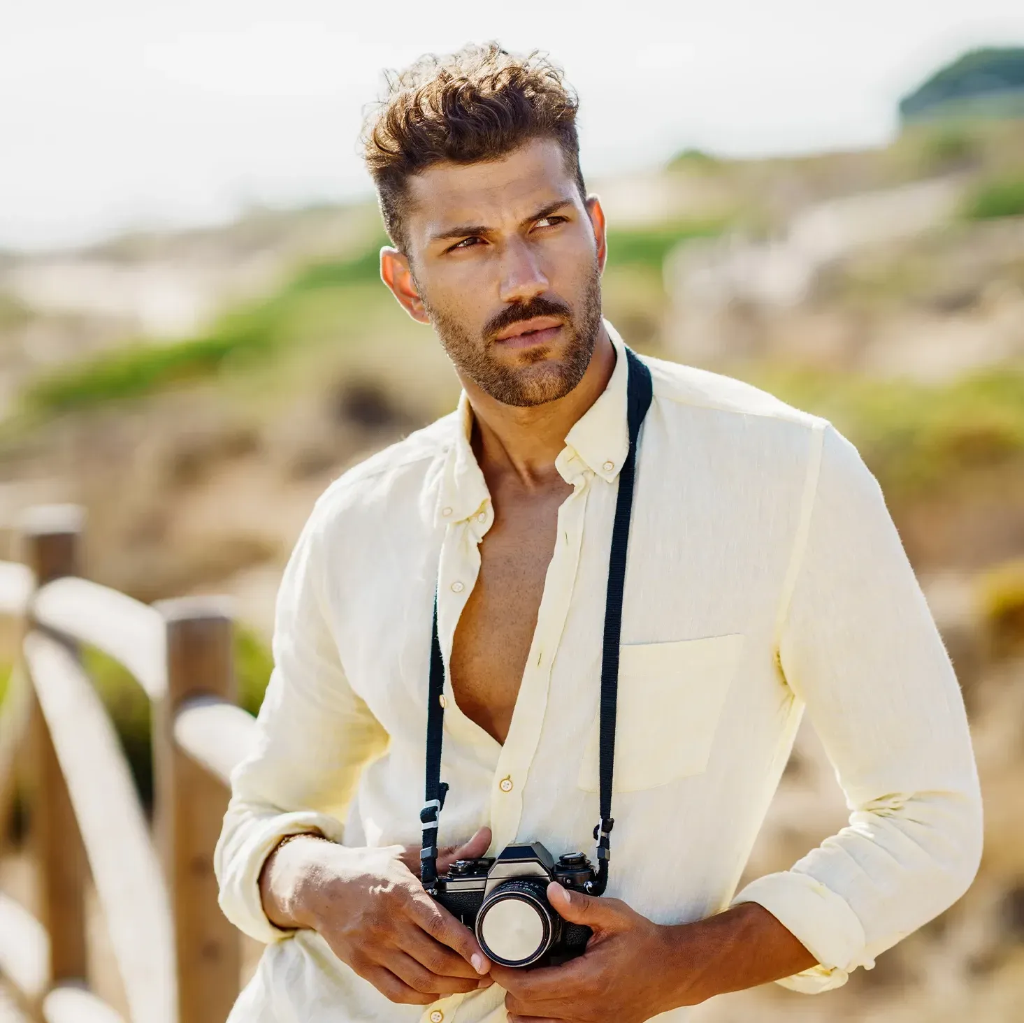 Male TV star posing for a photoshoot with a camera around his neck