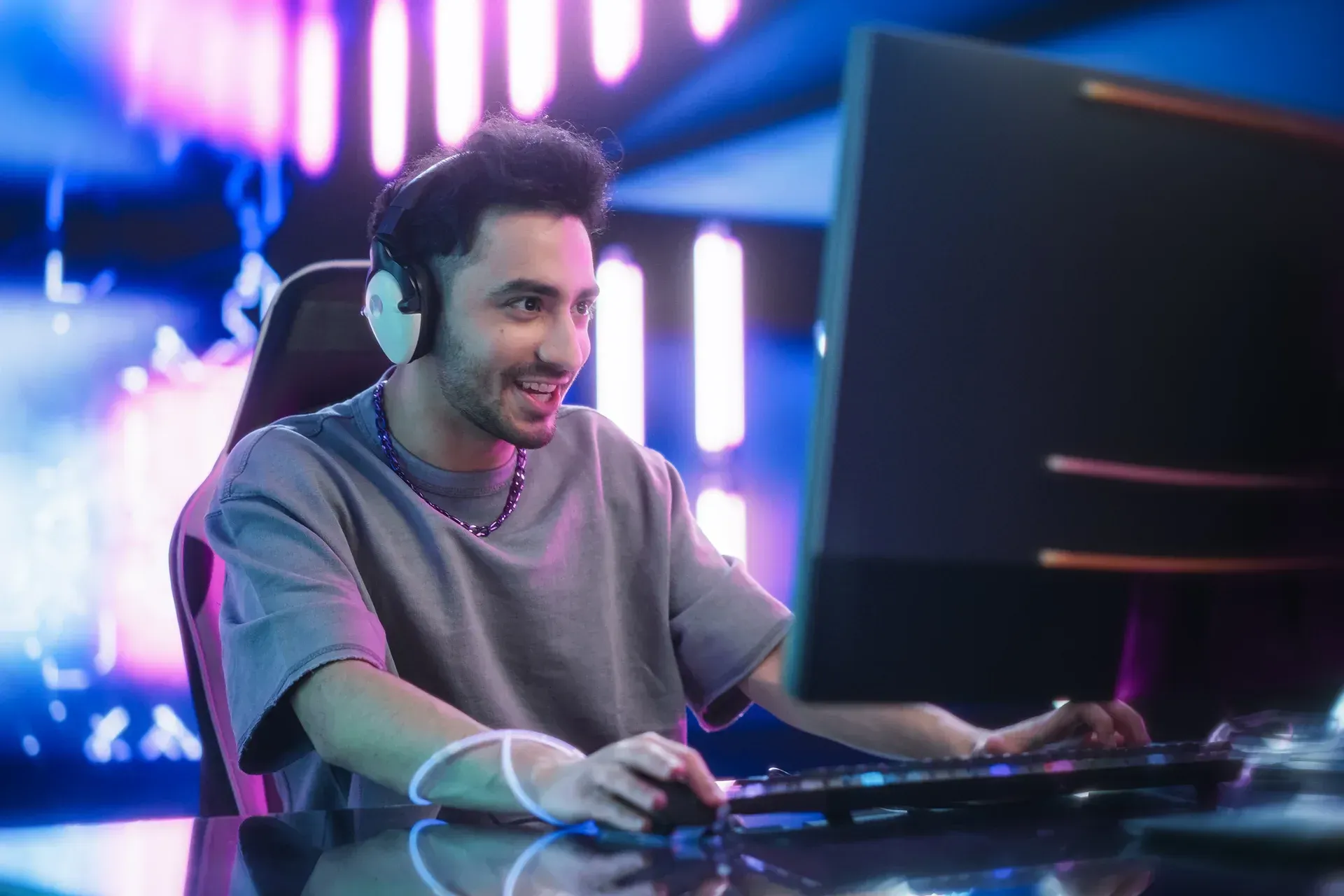 A gamer wearing headphones is playing a video game on his computer.