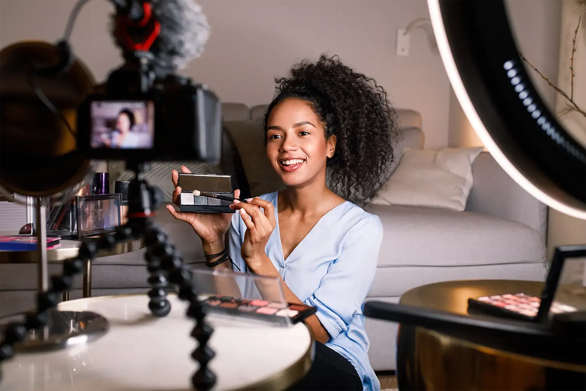 A female content creator is sitting on the floor filming a makeup tutorial
