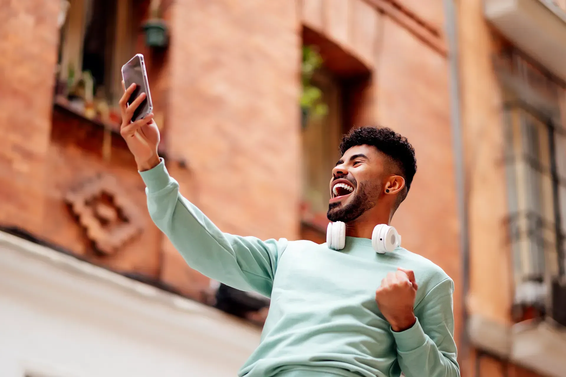 TikTok creator celebrating when creating content outdoors against a brick building