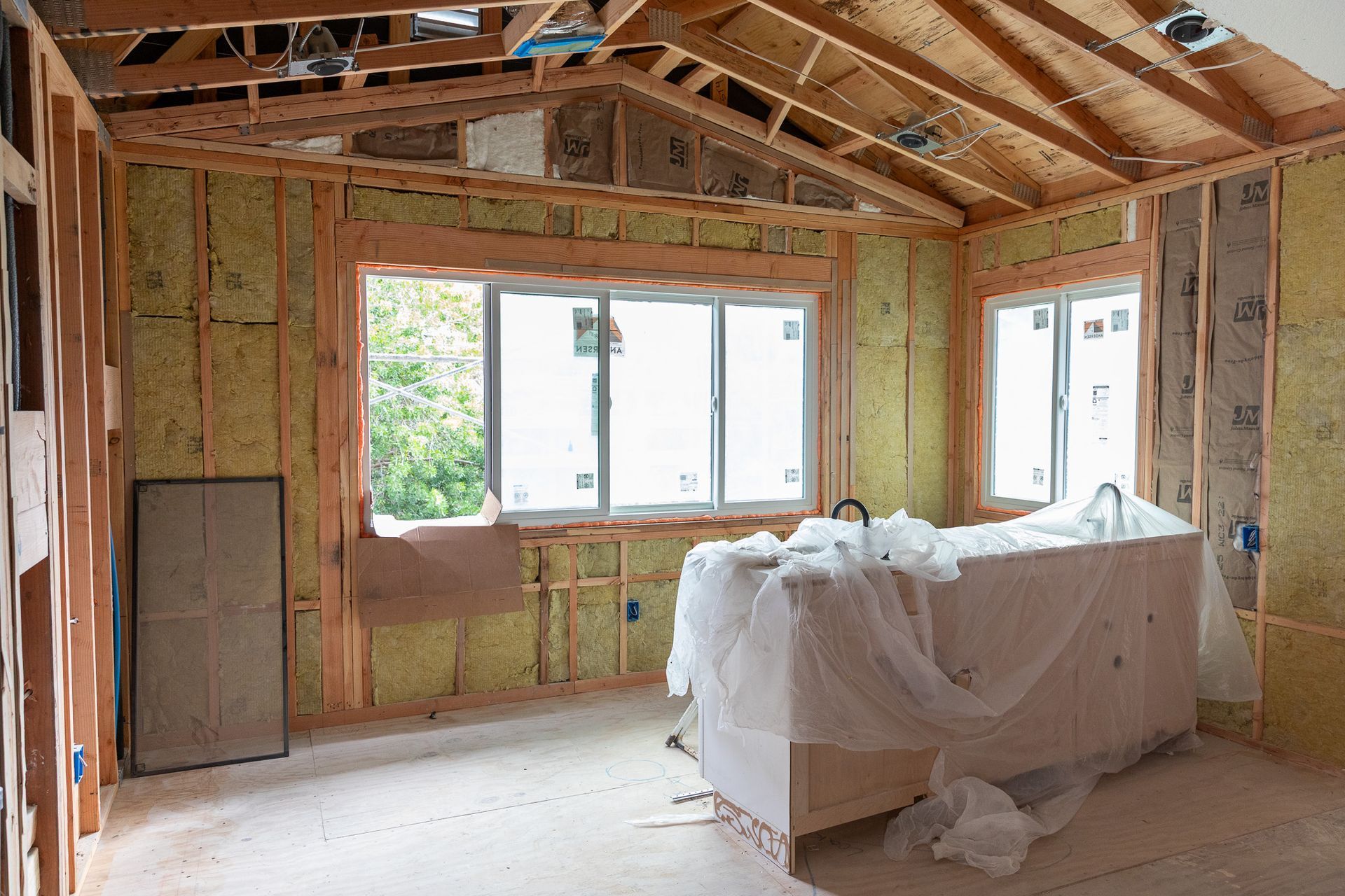 A room in a house under construction with a bathtub and a couch.