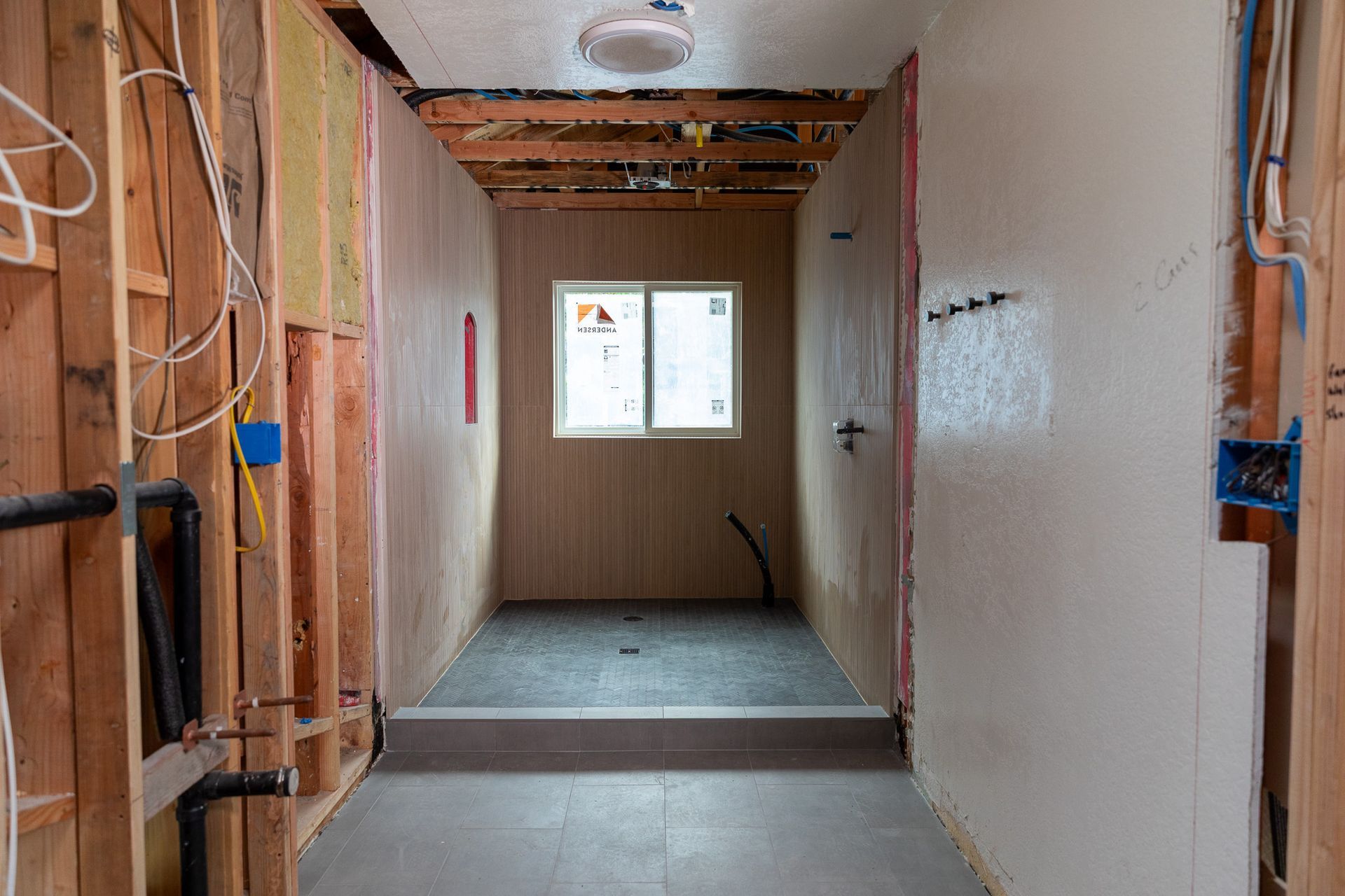 A hallway in a house under construction with a window.