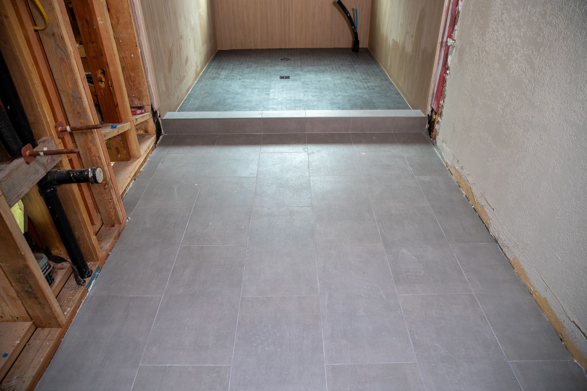 A bathroom under construction with a tiled floor and a walk in shower.