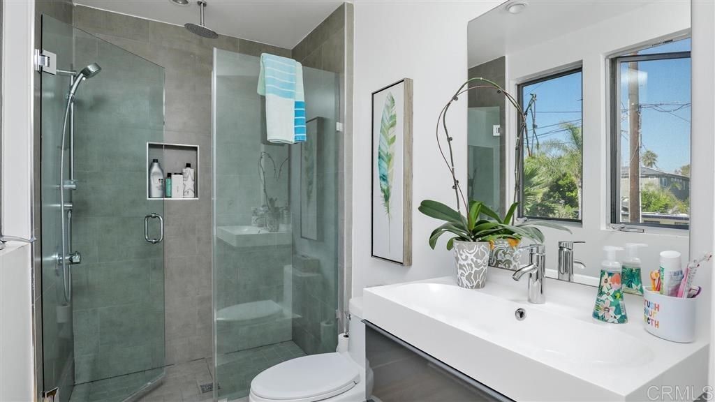 A bathroom with a toilet , sink , shower and mirror.