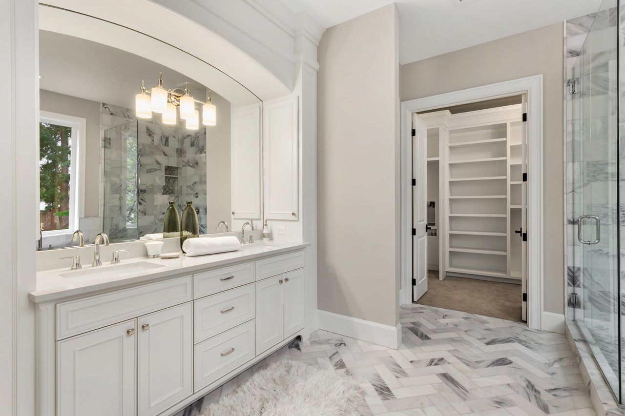 A bathroom with two sinks and a walk in closet.