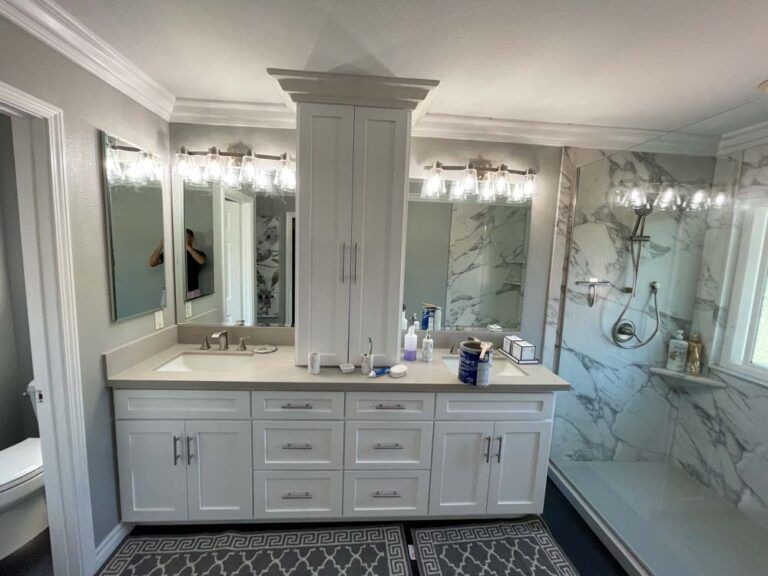 A bathroom with two sinks , two mirrors and a shower.