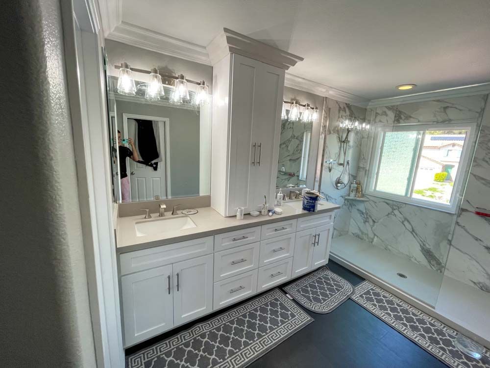 A bathroom with two sinks , two mirrors and a walk in shower.