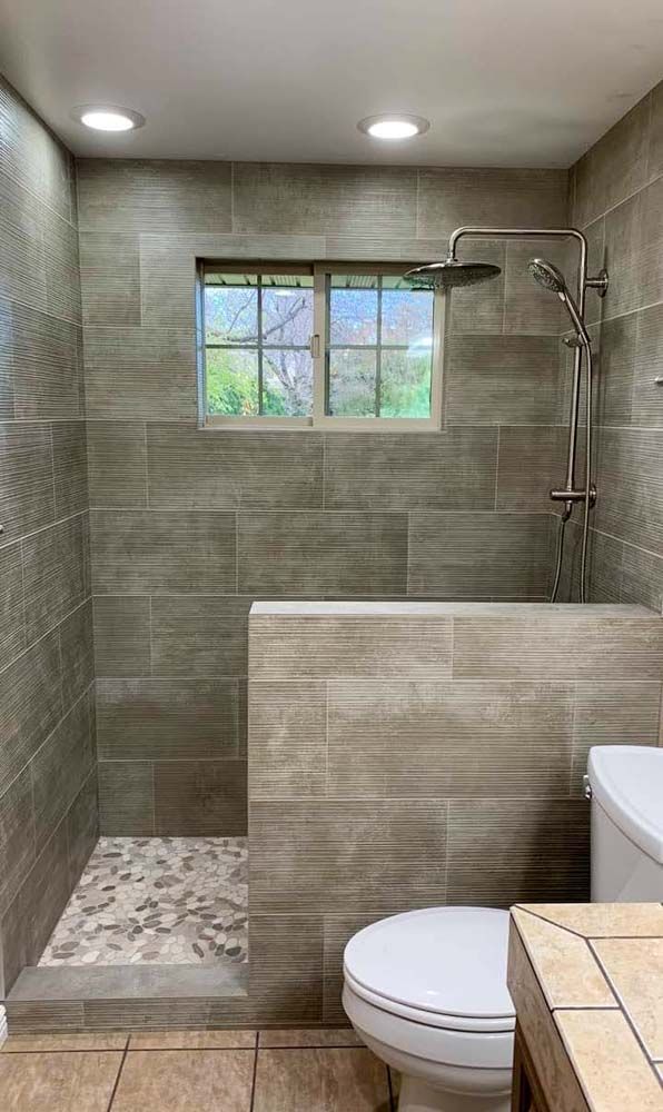 A bathroom with a toilet , shower , and window.