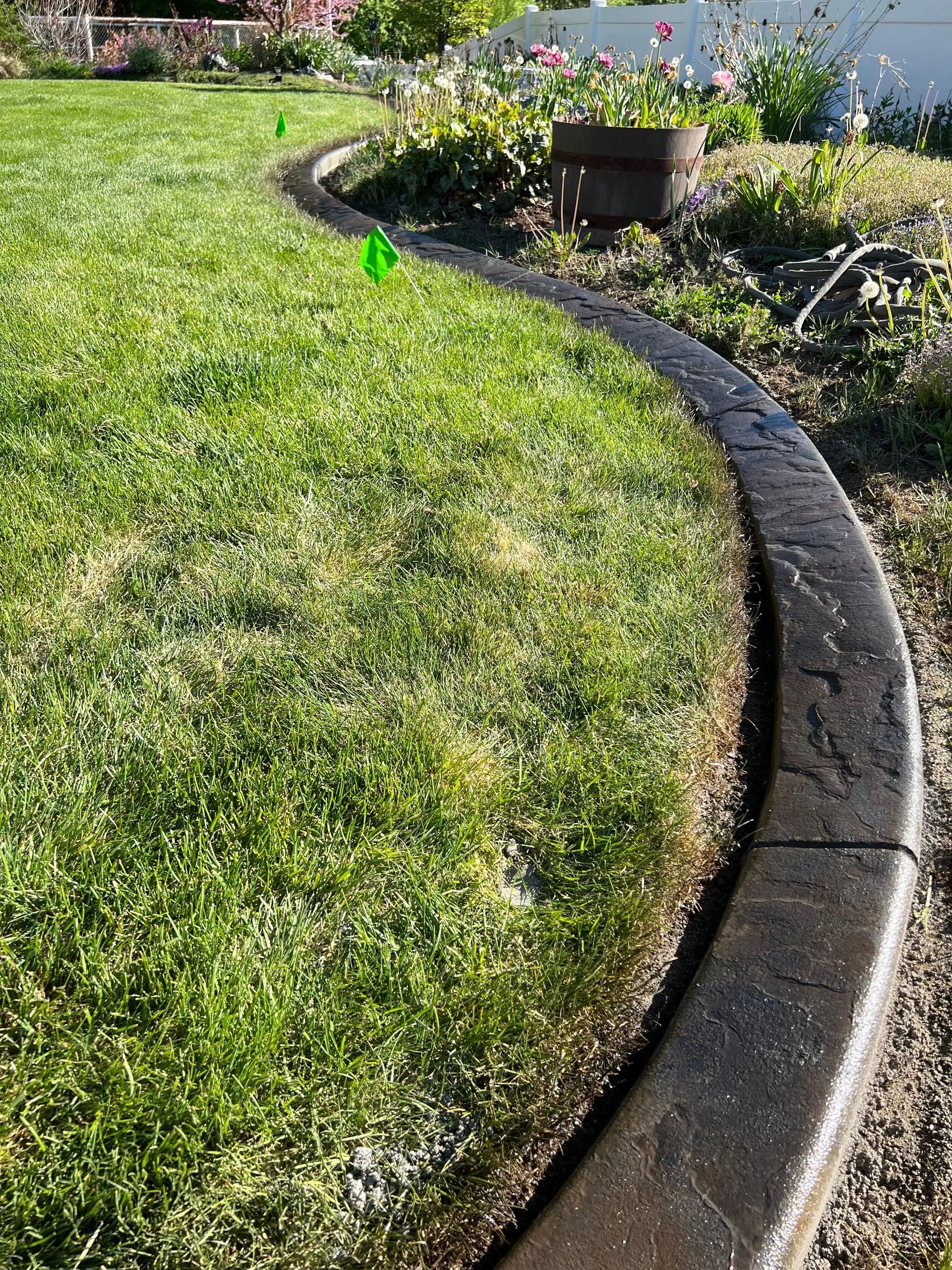 Curved concrete border edging lush green lawn.