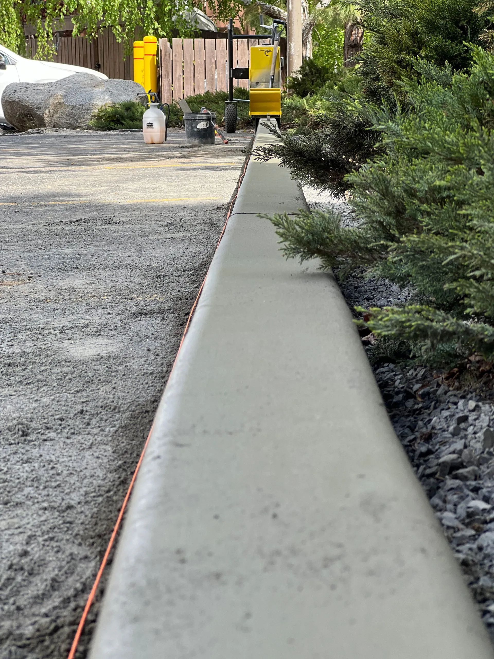 Freshly poured concrete curb alongside gravel pathway.
