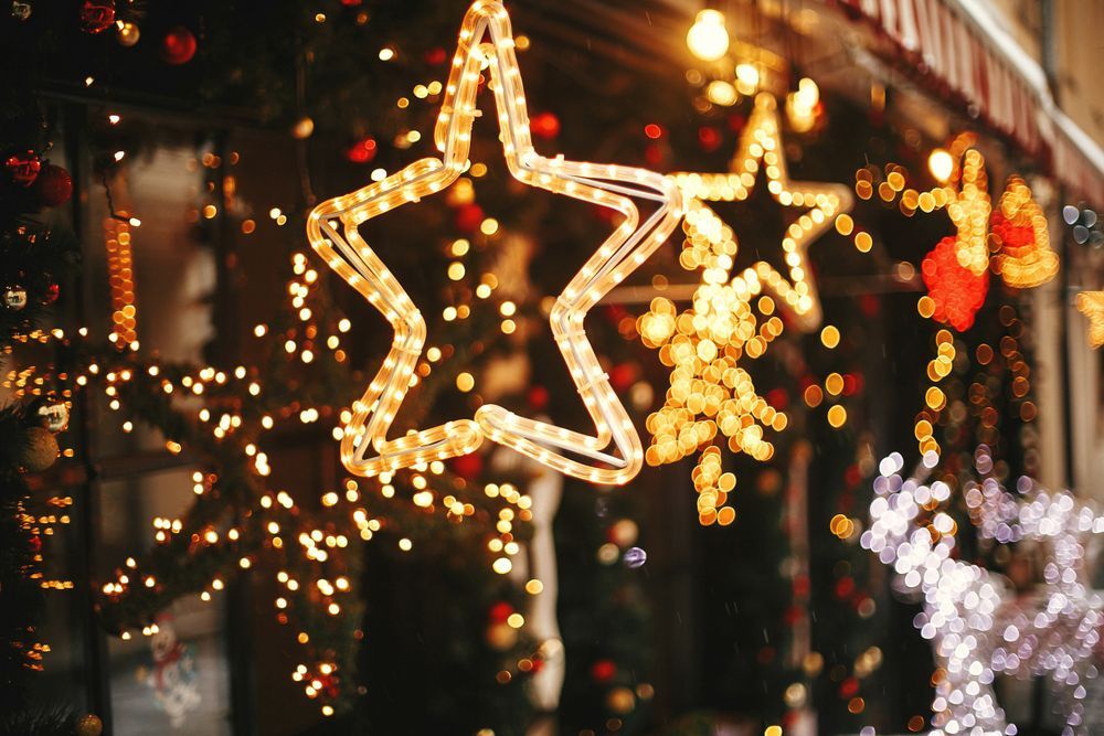 Window display with illuminated star and string lights. Festive, warm tones, blurry background.