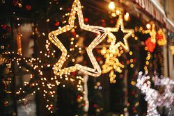 Window display with illuminated star and string lights. Festive, warm tones, blurry background.