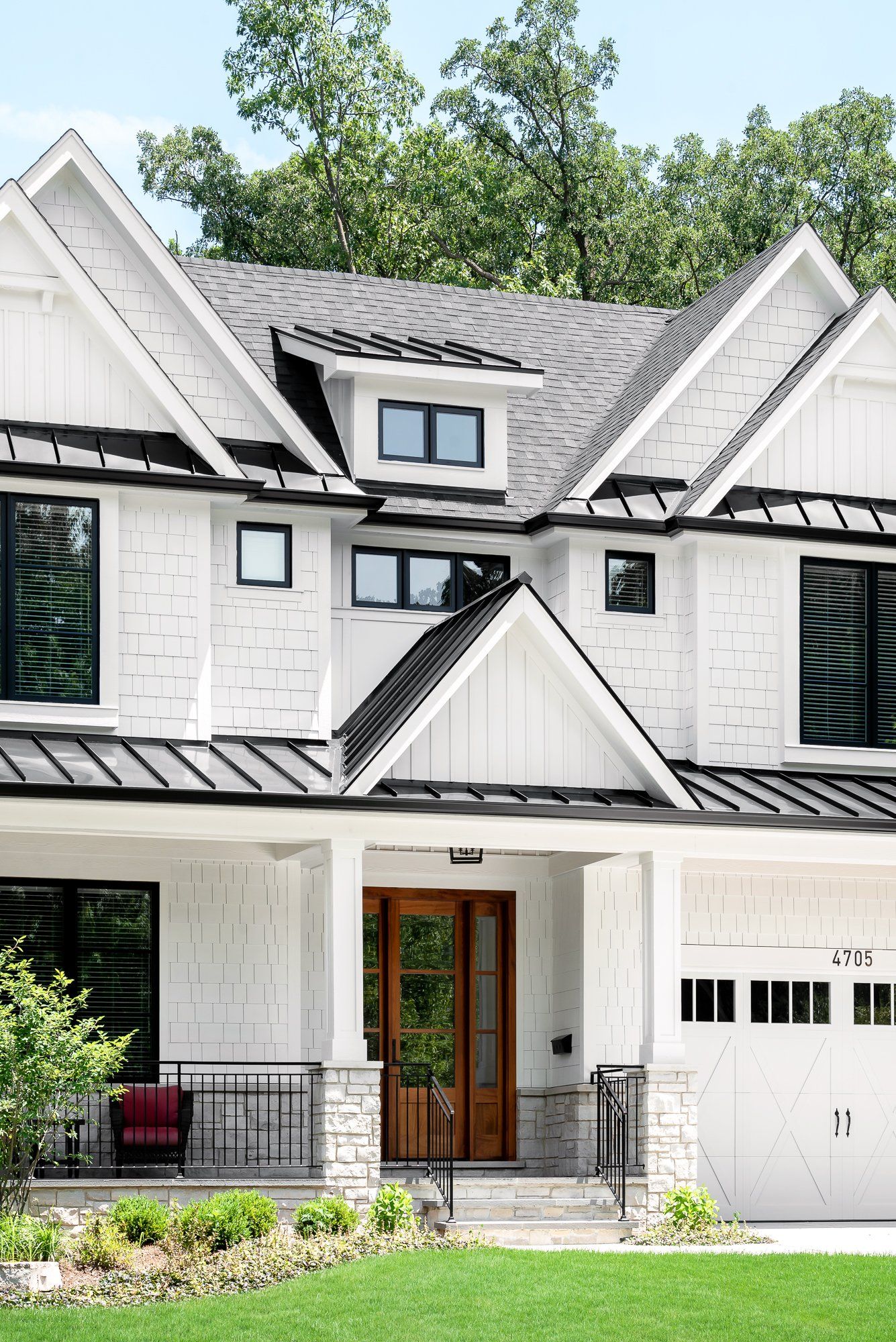 A large white house with a black roof and a large porch.