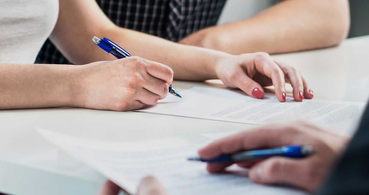 A man and a woman are sitting at a table writing on a piece of paper.