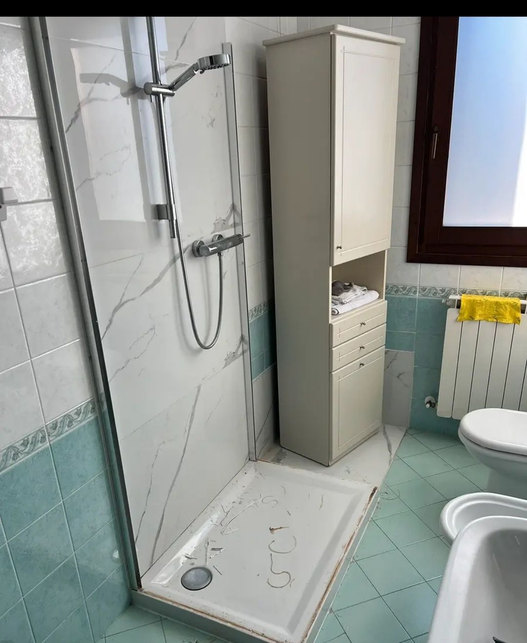 Bagno accessibile con doccia, sedia da doccia, mobiletto e zona lavabo con WC.