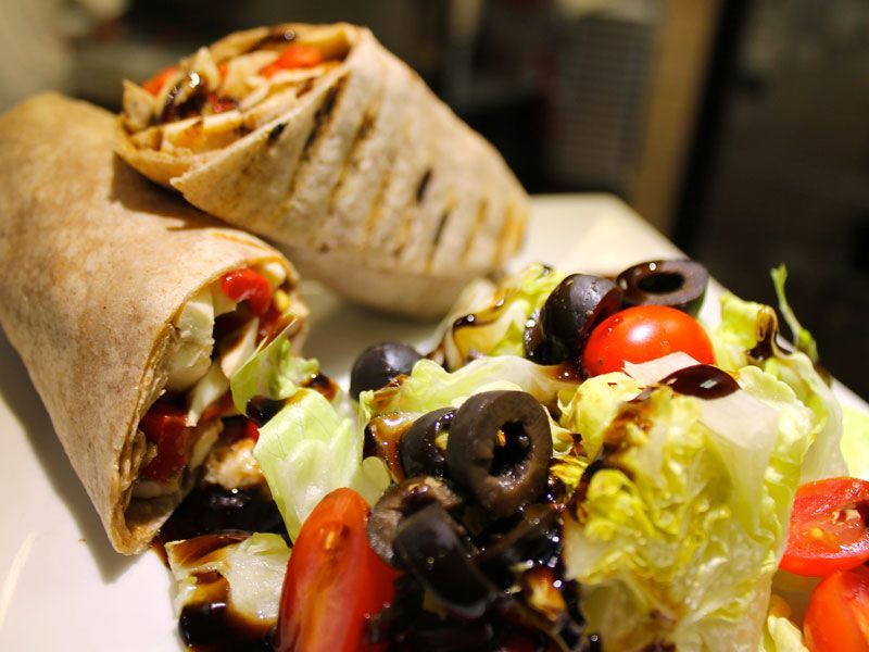 Wrap sandwiches with salad, tomatoes, and black olives.